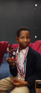 Jayce Joyce holding the TruLittle Hero Award trophy at an awards ceremony